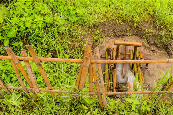 Water flowing from irrigation pipe spinning a small water wheel in canal in Chiang Khan, Thailand,