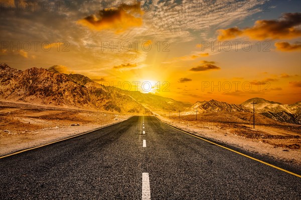 Travel forward concept background, road in Himalayas with mountains and dramatic clouds on sunset.