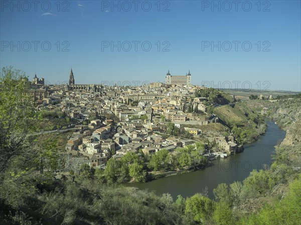 View of a historic riverside town with distinctive church towers and bridges, framed by hills under