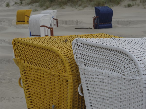 Close-up of yellow and white beach chairs on a sandy beach in cloudy weather, colourful beach