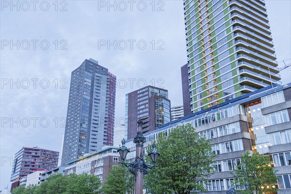 City view with modern skyscrapers, a lamp post in the foreground and trees in a cloudy sky, small