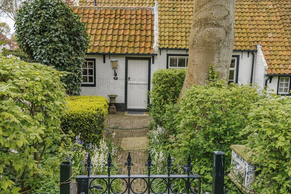 Charming house with garden and red tiled roof, surrounded by bushes, old houses with green gardens