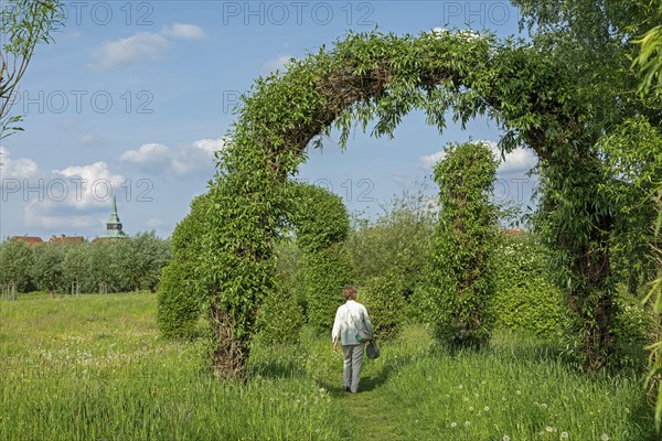 Woman goes for a walk, Topiary Garden, Symphonic Willow Walk, Boizenburg, Mecklenburg-Vorpommern,