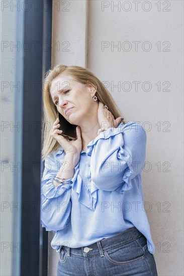 Tired woman talking on the phone with neck pain