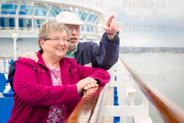 Senior adult couple enjoying the view from their passenger cruise ship railing