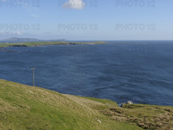 View of a wide green plain sloping down to the deep blue sea, green meadows by a deep blue sea and