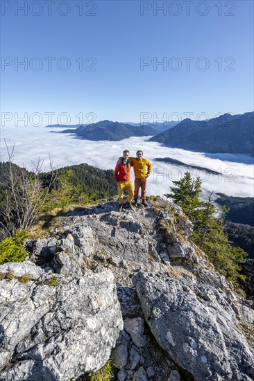 Two friends put their arms around each other's shoulders, mountaineers on the rocky summit of the