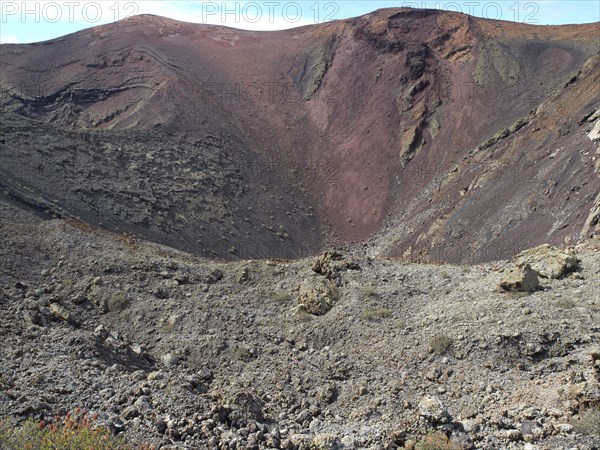 A broad volcano with a crater and red earth tones in a barren landscape, barren landscape with