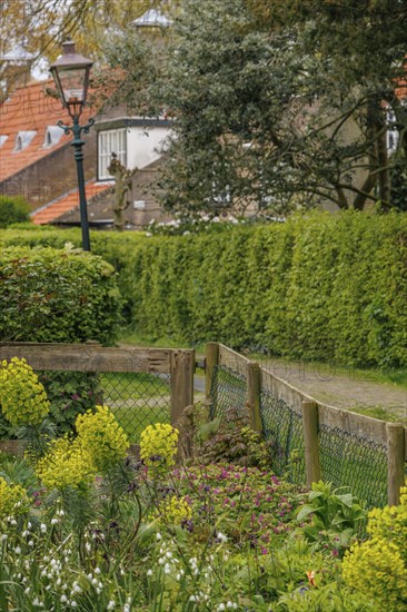 A well-maintained wooden fence with blossoming railing flowers lining the quiet village street, old