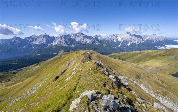Mountaineers on a hiking trail between green mountain meadows on a mountain ridge, mountain