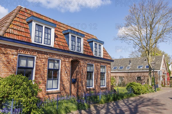 A large brick house with red tiled roofs and white window frames in a quiet street, historic houses
