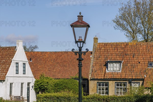 Historic houses with tiled roofs and a street lamp in a village in spring, historic houses in a