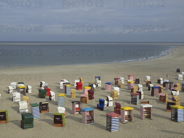View of numerous colourful beach chairs on the wide beach under a cloudy sky, beach chairs and