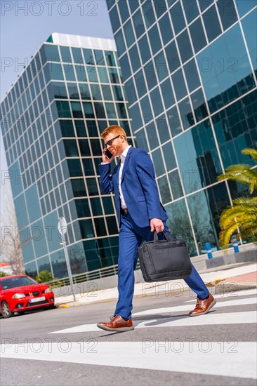 Vertical full length photo of a cool businessman talking to the mobile walking along the city
