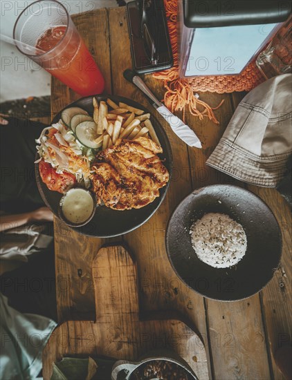 Top view of traditional roast chicken with french fries and salad served on wooden table