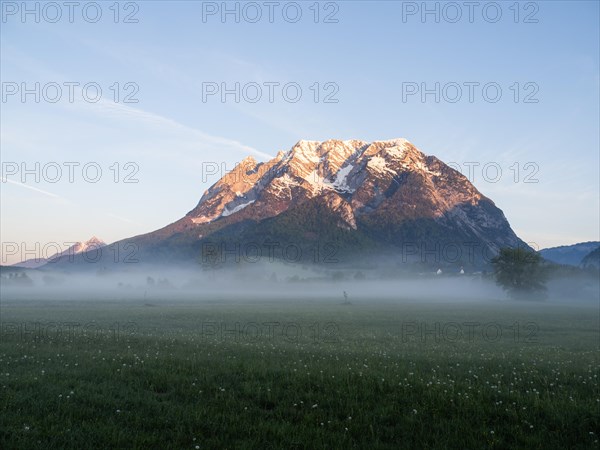 Morning light falls on a mountain peak, Grimming, early morning fog on the meadow, near Irdning,