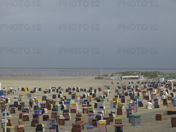 Numerous colourful beach chairs are located in large numbers on the empty beach with a wide view of