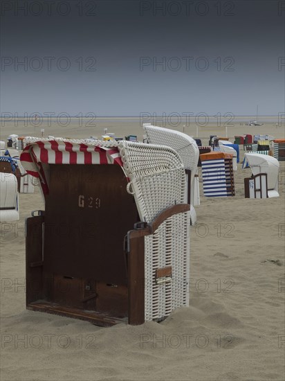A single beach chair stands on a deserted beach under a cloudy sky, beach chairs and beach tents by