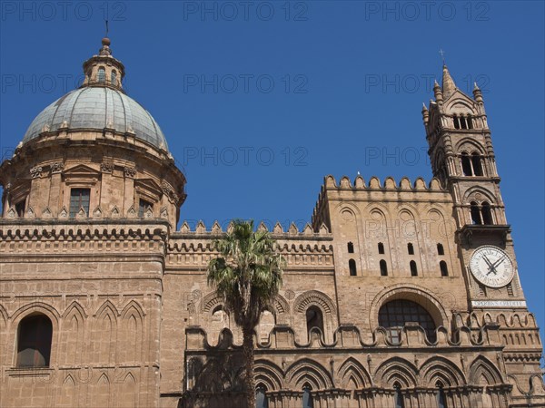 Side view of a historic cathedral with a striking dome and a clock on the tower, against a blue