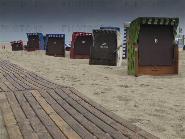 Beach chairs and a wooden jetty on the beach with a cloudy sky and a view of the sea, beach chairs