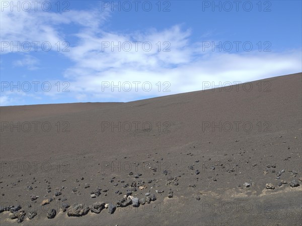 Vast desert landscape with blue sky and dry, stony ground, barren landscape of lava mountains,