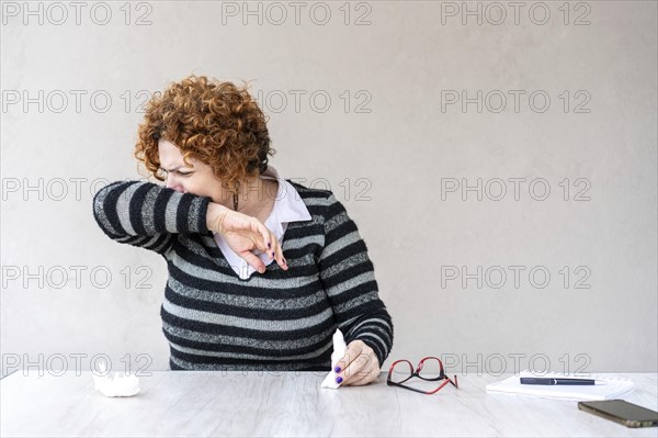 Woman sneezes and covering his sneezes and coughs into his bent elbow
