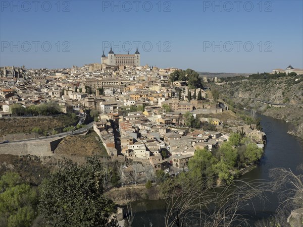 Wide view of a historic city on a river with characteristic church towers and bridges, hills and a