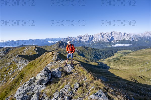 Mountaineer on a grassy ridge, mountain panorama, view of rocky mountain peaks of the Sesto