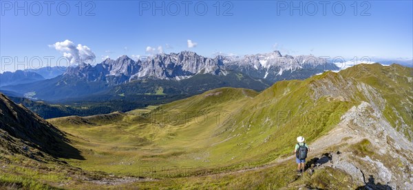 Mountaineers on a hiking trail between green mountain meadows on a mountain ridge, mountain
