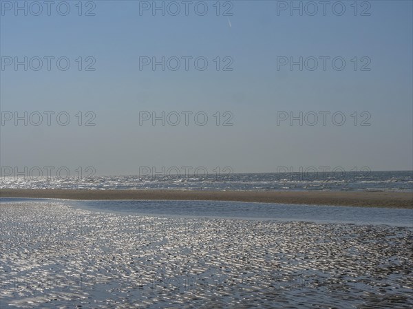Spacious beach and calm sea under a clear blue sky, sparkling sea water at low tide on the beach,