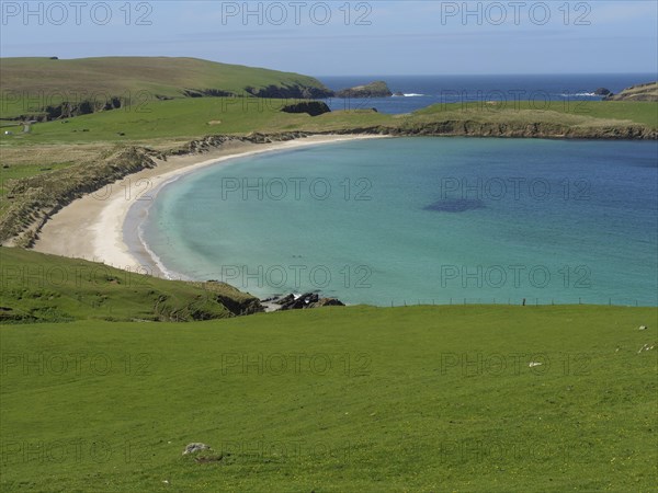 A picturesque stretch of coastline with rolling hills, a golden beach and turquoise waters blending
