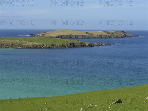Peaceful island in the blue ocean with green grassland and blue skies. The atmosphere is calm and
