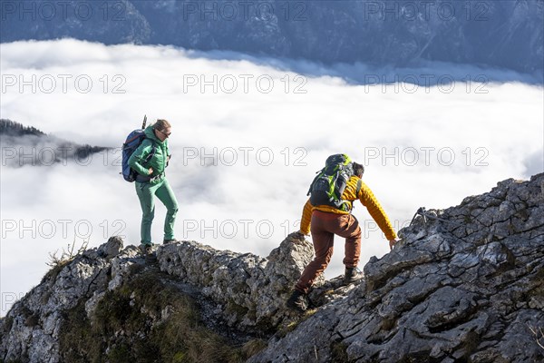 Two hikers at Ettaler Manndl, view over mountain landscape and sea of clouds, high fog in the