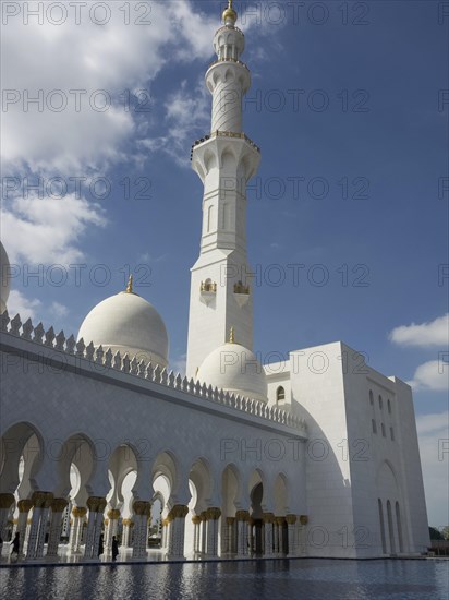 Beautiful mosque with white domes and minarets under a clear blue sky with clouds, large mosque