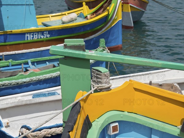 Colourful boats moored side by side at the pier in the clear waters of a harbour, many colourful