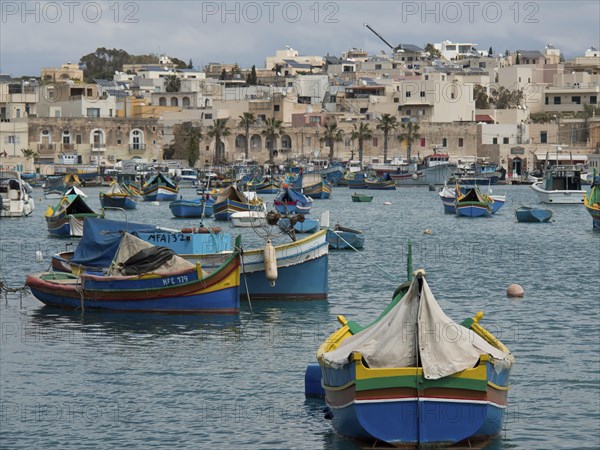 View of a multitude of fishing boats in a busy harbour off the coast of a town, many colourful