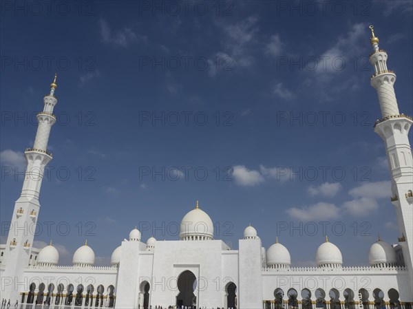 Large mosque with white domes, minarets and golden decorations under a blue sky, beautiful mosque