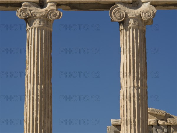 Close-up of ancient marble columns and their details against a clear blue sky, historical columns