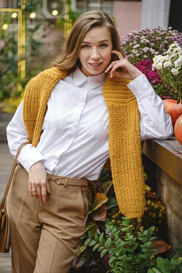Outdoor portrait of cute lovely woman at an autumn fair leaning on a wooden display table