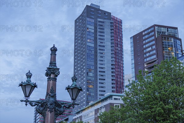 City view with modern skyscrapers and an old lamp post in the foreground under a blue sky, small