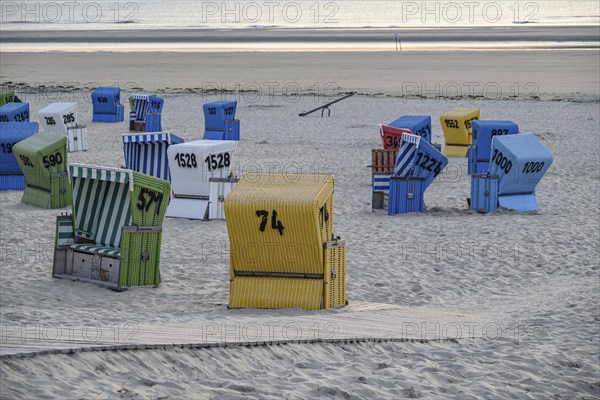 A quiet and relaxing beach evening with colourful beach chairs, a wooden walkway and soft sand,