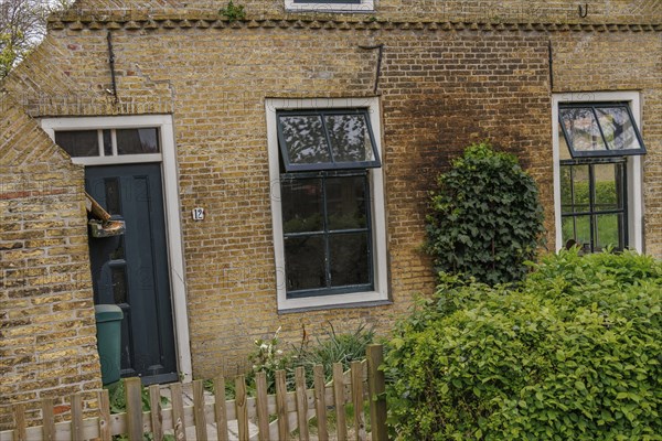 Quiet village life represented by a charming brick house with ivy-covered walls, old houses with