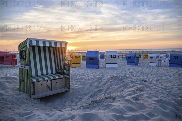 Colourful beach chairs on the beach at sunset, an open basket in the foreground, many colourful