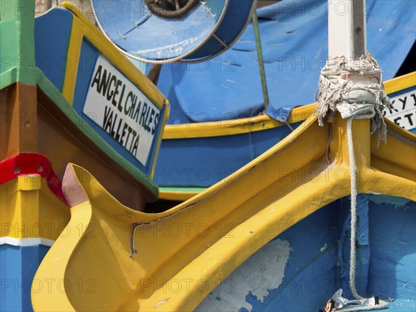 Colourful fishing boats in the harbour with different coloured details and a sign, many colourful