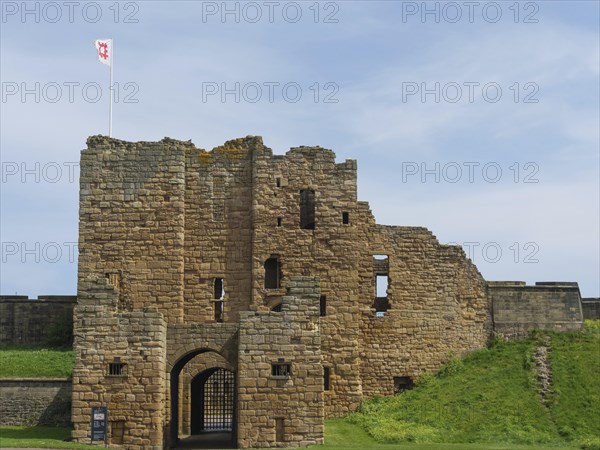Close-up of a castle ruin with medieval architecture and a flag in the wind under a blue sky, ruins