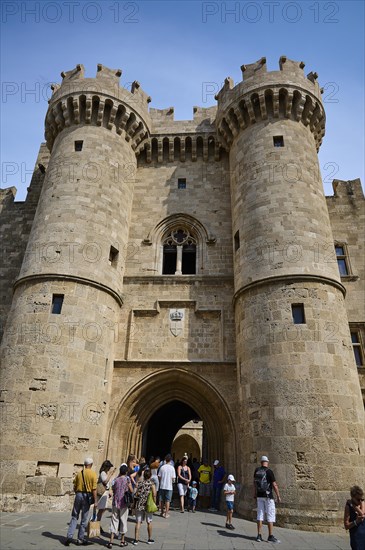 Super wide angle shot, portrait format, tourists enter through a large portal crowned with