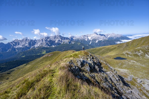 Mountaineers on a hiking trail between green mountain meadows on a mountain ridge, mountain