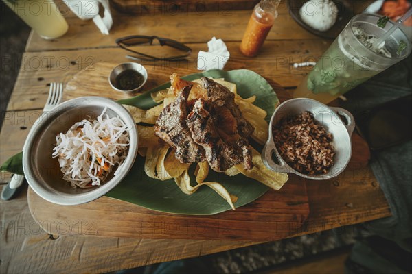 Traditional roast beef with slices of banana and gallopinto served on a wooden table. Wooden table