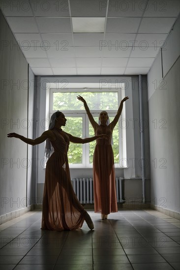 Silhouette of two female dancers rehearsing choreography in the hallway of theatre