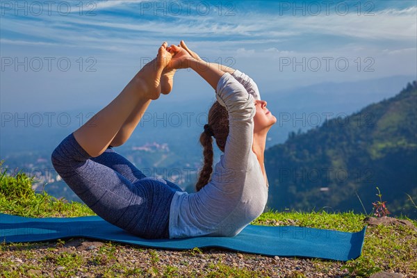 Yoga outdoors, young woman doing Ashtanga Vinyasa Yoga asana Dhanurasana, bow pose, in Himalayas